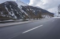 a snow covered mountain is in the background while a car drives down the road in a blur