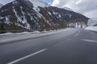 a snow covered mountain is in the background while a car drives down the road in a blur