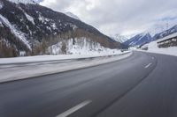 a snow covered mountain is in the background while a car drives down the road in a blur