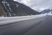 a snow covered mountain is in the background while a car drives down the road in a blur