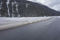 a snow covered mountain is in the background while a car drives down the road in a blur