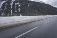 a snow covered mountain is in the background while a car drives down the road in a blur