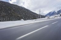 a snow covered mountain is in the background while a car drives down the road in a blur