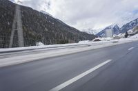 a snow covered mountain is in the background while a car drives down the road in a blur