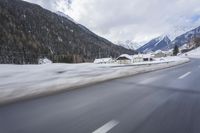 a snow covered mountain is in the background while a car drives down the road in a blur