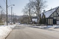 an empty street has many snow piles on the side and trees and power lines at each end