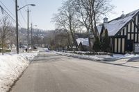 an empty street has many snow piles on the side and trees and power lines at each end