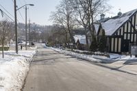 an empty street has many snow piles on the side and trees and power lines at each end