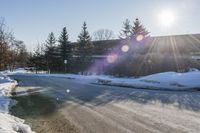 the sun is peeking out onto the snow covered street as seen in the picture above