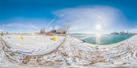 a snow covered beach with ice on the water and snow drifts all around it