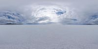 a snow covered beach with a sky and clouds in the background that appear to be in motion