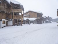 a city street with some brown houses in the background and snow covering the ground outside