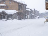 a city street with some brown houses in the background and snow covering the ground outside