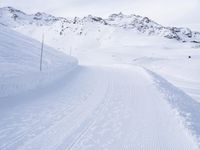 snow covered slope in the middle of a ski area as people ski on it near ski lift