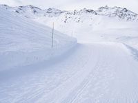 snow covered slope in the middle of a ski area as people ski on it near ski lift