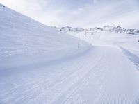 snow covered slope in the middle of a ski area as people ski on it near ski lift