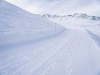 snow covered slope in the middle of a ski area as people ski on it near ski lift