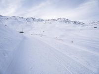 snow covered slope in the middle of a ski area as people ski on it near ski lift