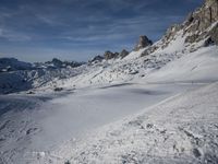 a group of people riding skis down a snow covered slope next to large mountains