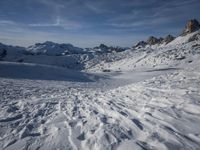 a group of people riding skis down a snow covered slope next to large mountains