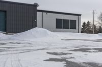 a parking meter is in the snow next to a building and an empty street in a country lane