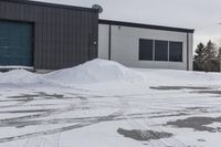 a parking meter is in the snow next to a building and an empty street in a country lane