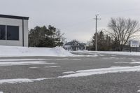 a parking meter is in the snow next to a building and an empty street in a country lane