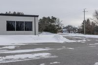 a parking meter is in the snow next to a building and an empty street in a country lane