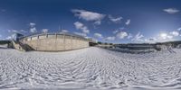 a panorama fish eye view of an outdoor stadium, showing snow and stairs, from the bottom down