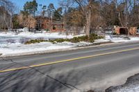 a street with snow on the ground next to a house and trees and a building