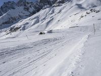 a snow skier traveling on a steep snowy slope with his skis on it's feet