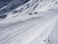 a snow skier traveling on a steep snowy slope with his skis on it's feet