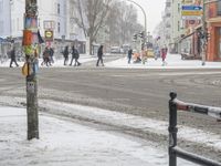 people crossing a street with several traffic lights in the snow on a city street on a snowy day