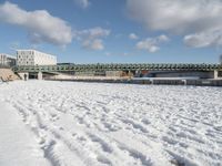 the bridge spans across the river into a city filled with snow and boats parked on it