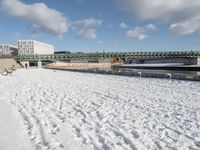 the bridge spans across the river into a city filled with snow and boats parked on it