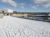 the bridge spans across the river into a city filled with snow and boats parked on it