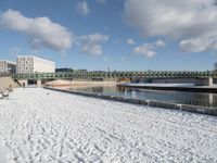 the bridge spans across the river into a city filled with snow and boats parked on it