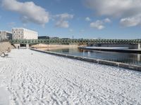 the bridge spans across the river into a city filled with snow and boats parked on it