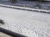 the view of a person sitting on a park bench covered in snow by a pool