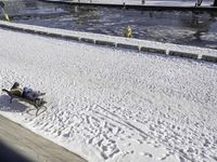 the view of a person sitting on a park bench covered in snow by a pool