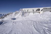 snow is covering the ground at the top of the mountain of a building with a walkway over it