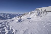 snow is covering the ground at the top of the mountain of a building with a walkway over it