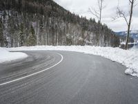 a very curvy road in the middle of the woods, covered with snow