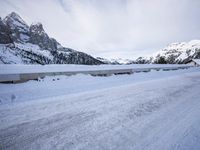 a snow covered mountain road next to the road with mountains in the background in the distance