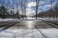 the empty street is covered in snow and has no cars on it with lots of trees