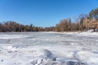 a wide angle view of a snow covered lake with lots of snow in front of it