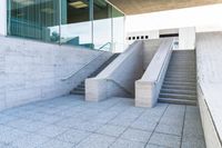 a group of stairs leading up to an entrance building on concrete steps are set in front of a glass wall