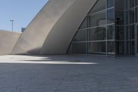 a woman on a bicycle in the middle of an outdoor courtyard with a glass building behind it