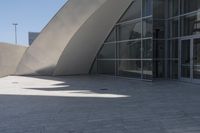 a woman on a bicycle in the middle of an outdoor courtyard with a glass building behind it