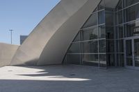 a woman on a bicycle in the middle of an outdoor courtyard with a glass building behind it